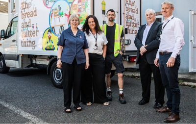 An image of the Bread and Butter Thing (TBBT) staff and volunteers stood outside a TBBT van. 