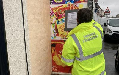 A Trading Standards officer posts a closure order notice onto outside of 103 Westbury Street shop for selling illicit cigarettes