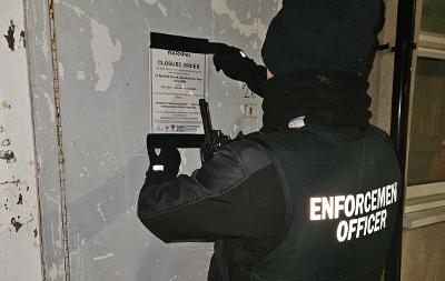 Enforcement officer putting up closure order notice at 31 Norfolk Street, Stockton