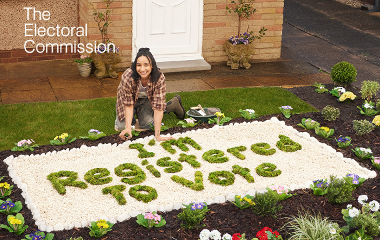 An image of a lady in her garden. The flowers in the garden say "I'm registered to vote"