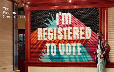 A man stood next to a shutter which says "I'm registered to vote"